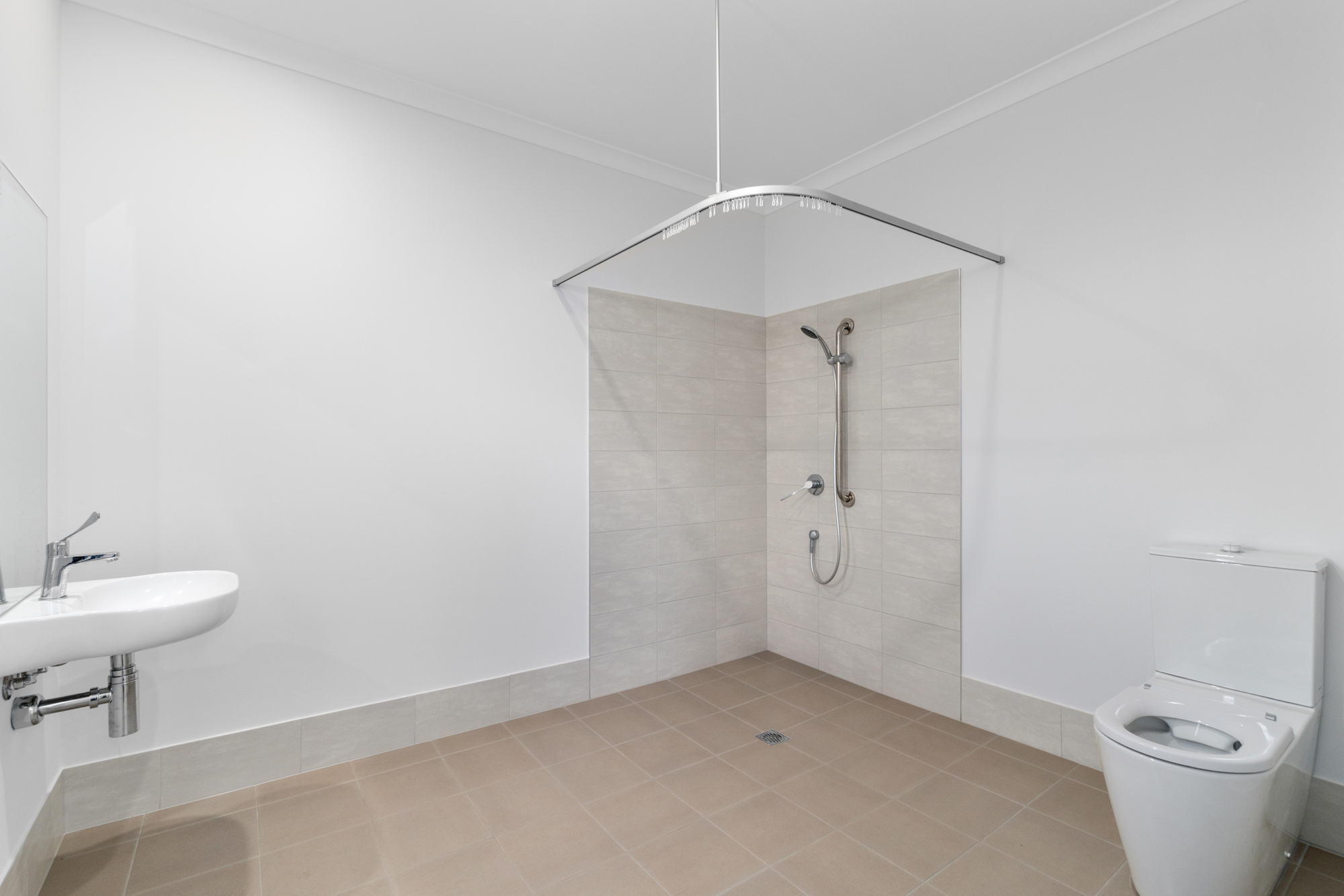 Large and light accessible ensuite bathroom with double shower, toilet and sink