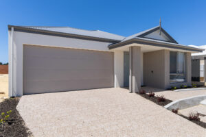 Front of a modern grey home with wide accessible driveway and ramp to front door including intercom and garden bed