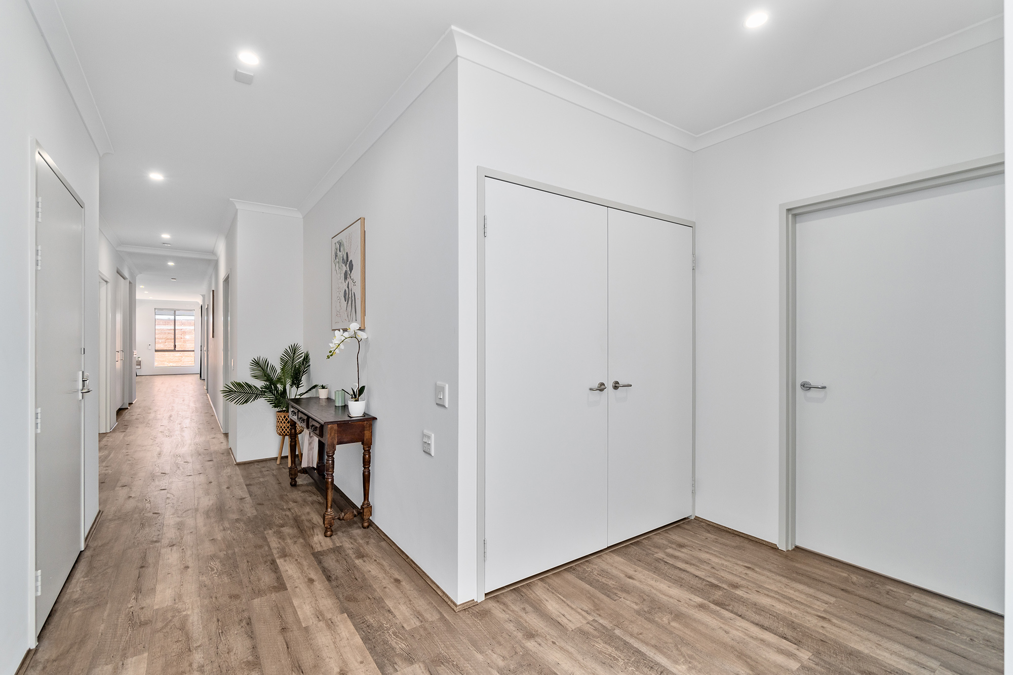 Light and bright white hallway with wide space for wheelchair and equipment, plus doors opening to storage space