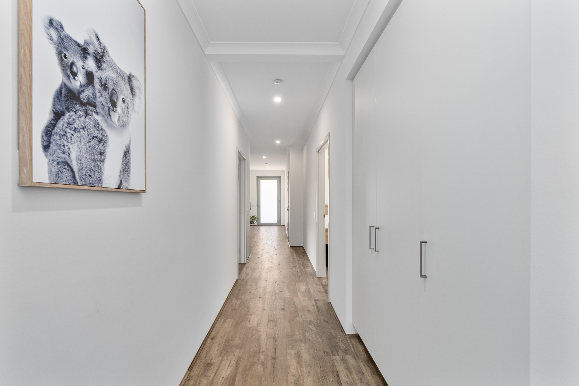 Light and bright white hallway with wide space for wheelchair and equipment, plus doors opening to storage space